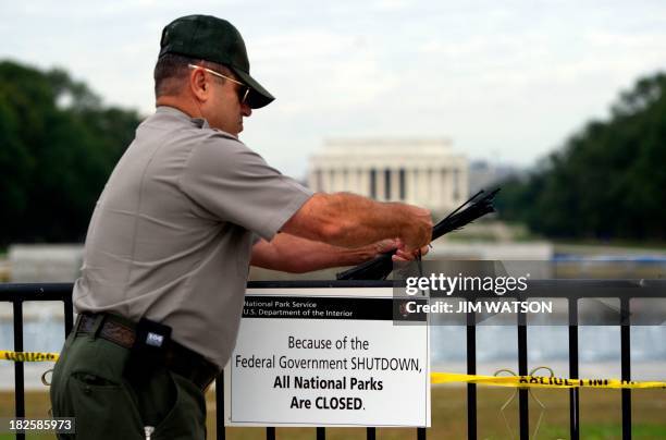 Park Ranger Richard Trott places a closed sign on a barricade in fron tof the World War II monument in Washington, DC, October 1 due to a US...