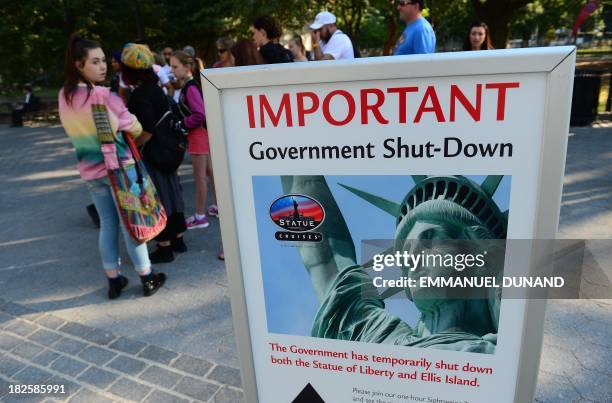 Tourists walk by a sign announcing that the Statue of Liberty is closed due to a US government shutdown in New York, October 1, 2013. Government...