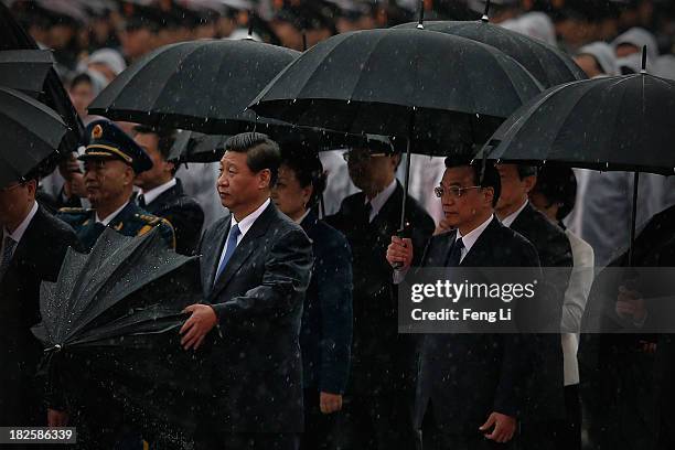 Chinese President Xi Jinping opens his umbrella as Premier Li Keqiang and Chinese Communist Party top leaders stand with umbrellas in the rain after...