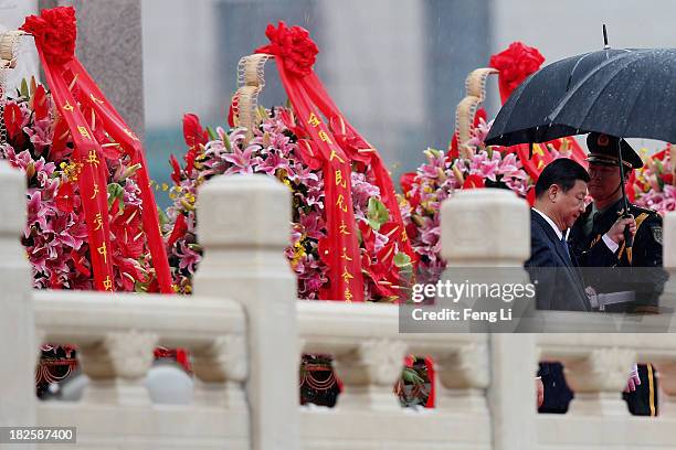 Chinese President Xi Jinping pays tribute in rain on the Monument to the People's Heroes during a ceremony marking the 64th anniversary of the...