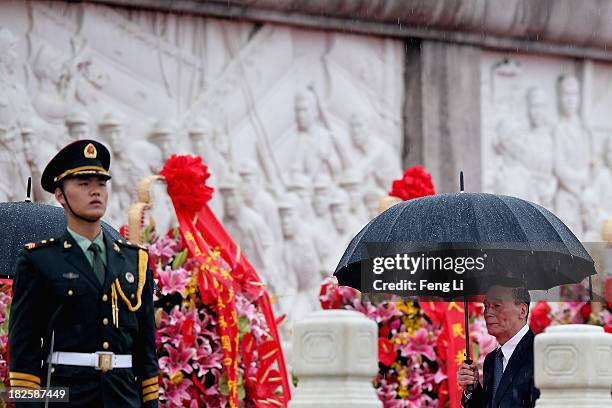 Secretary of the Central Commission for Discipline Inspection Wang Qishan walks past the Monument to the People's Heroes while holding umbrella...