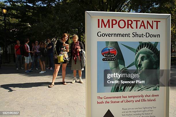 People look at a sign for informing that the Statue of Liberty is closed due to the government shutdown in Battery Park on October 1, 2013 in New...