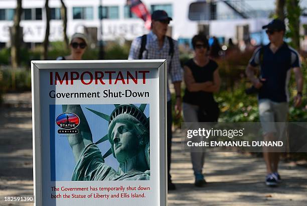 Tourists walk by a sign announcing that the Statue of Liberty is closed due to an US government shutdown in New York, October 1, 2013. Government...