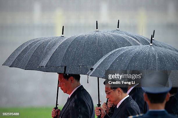 Chinese President Xi Jinping , Premier Li Keqiang and Chinese Communist Party top leaders hold their umbrellas in the rain as they walk to the...