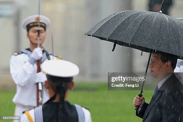 Chinese President Xi Jinping and Chinese Communist Party top leaders hold their umbrellas in the rain as they walk to the Monument to the People's...