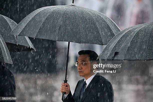 Chinese Premier Li Keqiang and Chinese Communist Party top leaders hold their umbrellas in the rain as they walk to the Monument to the People's...