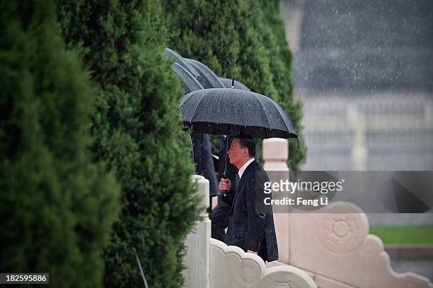 Secretary of the Central Commission for Discipline Inspection Wang Qishan and Chinese Communist Party top leaders hold their umbrellas in the rain as...