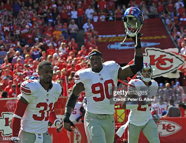 Players Jason Pierre-Paul, Aaron Ross and Terrell Thomas of the New York Giants run onto the field before a game against the Kansas City Chiefs on...