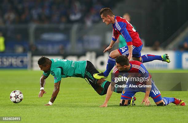 Kevin Prince Boateng of Schalke is challenged by Fabian Schaer and Taulant Xhaka of Basel during the UEFA Champions League Group E match between FC...