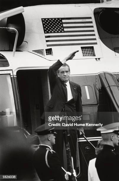 President Richard Nixon stands on the steps of the presidential helicopter as he waves goodbye to the White House for the final time after resigning...