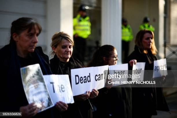 Protesters holds a placard reading "The dead can't hear your apologies" duing a gathering outside the UK Covid-19 Inquiry building in west London, on...