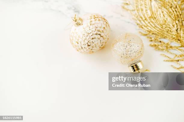 goldish christmas toy balls and a feather lying on light marbled surface . - yule marble stock pictures, royalty-free photos & images