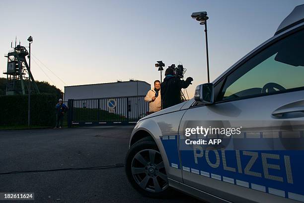 Camera team and a police car stand in front of the Schacht Unterbreizbach 2 head gear at the K + S potash company's plant in Unterbreizbach, eastern...