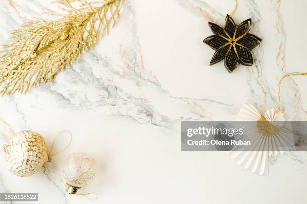 christmas toy balls and feather, star flower and paper angel lying on light marbled surface. - yule marble stock pictures, royalty-free photos & images