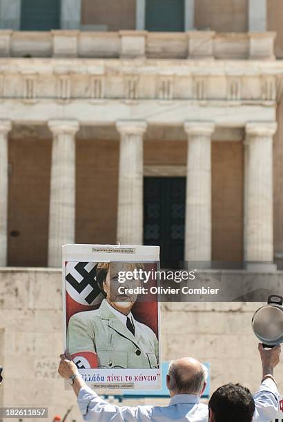 May 1st demonstration in Athens in front of the Greek parliament. A panel with Angela Merkel wearing mustache and suit Adolf Hilter is brandished by...