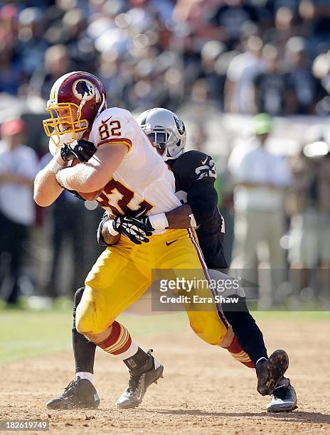 Logan Paulsen of the Washington Redskins is tackled by Tracy Porter of the Oakland Raiders at O.co Coliseum on September 29, 2013 in Oakland,...