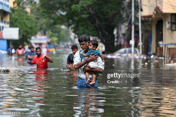 People wade through a flooded street after heavy rains in Chennai on December 6, 2023. Chest-high water surged down the streets of India's southern...