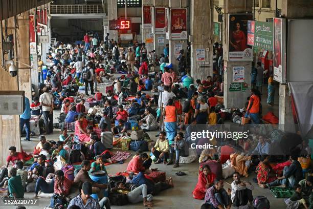 Stranded passengers gather at a railway station while waiting for their trains after heavy rains in Chennai on December 6, 2023. Chest-high water...