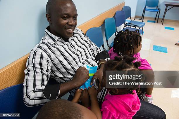 John Kavyavu of Takoma Park tries to hold onto an affordable care act pamphlet he was given by a presenter. Children from left to right are David...