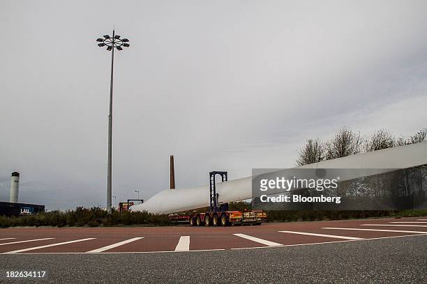 Truck crosses a parking lot as it delivers a blade for a wind turbine, manufactured by Vestas Wind Systems A/S, near the harbor at the company's...