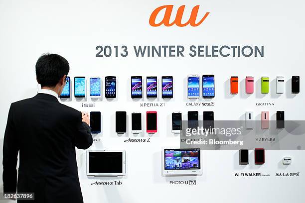 An attendant arranges KDDI Corp.'s "au" brand of smartphones displayed with other mobile devices during a product launch event in Tokyo, Japan, on...