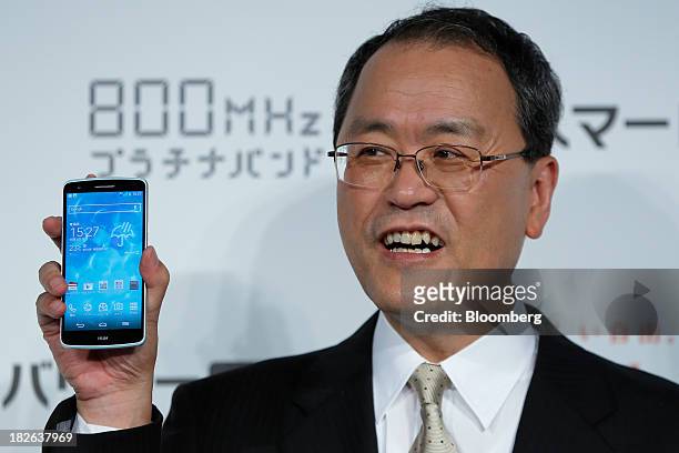 Takashi Tanaka, president of KDDI Corp., holds the company's "au" brand smartphone, the Isai LGL22 manufactured by LG Electronics Inc., during a...