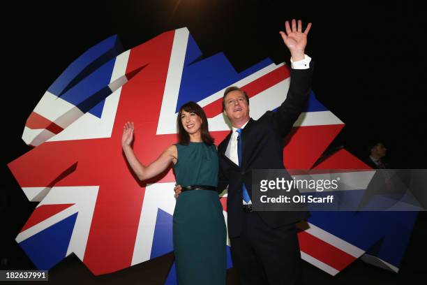 British Prime Minister David Cameron waves to the audience with his wife Samantha after delivering his keynote speech on the last day of the annual...