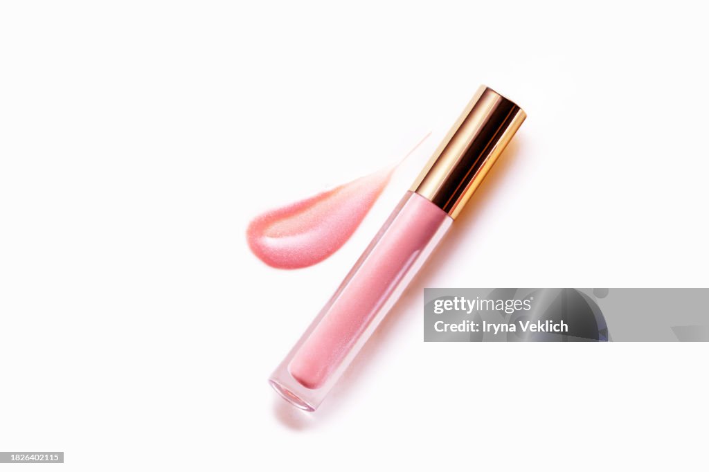 Shiny pastel Pink Colour smear of Lip Gloss or Liquid Blush with bottle with Applicator on white background.