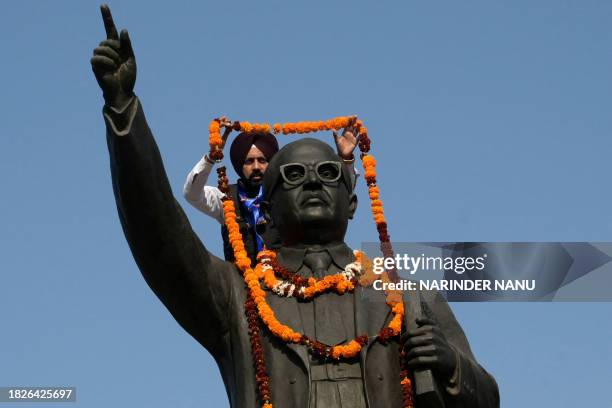 An activist of Bahujan Samaj Party garlands a statue of Indian social reformer Bhimrao Ambedkar on the occasion of his death anniversary, in Amritsar...