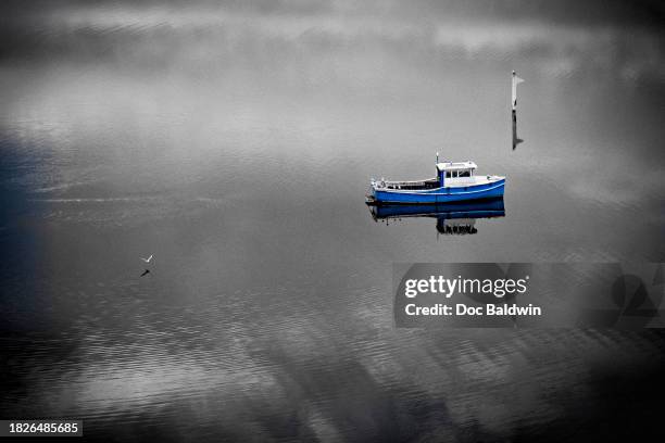 a blue boat, in spot colour, with a black and white treatment. - isolated color stock pictures, royalty-free photos & images