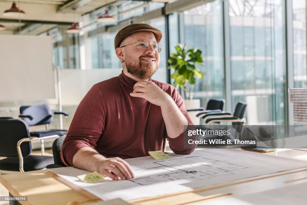 Architect Sitting At Desk Working On Building Plans