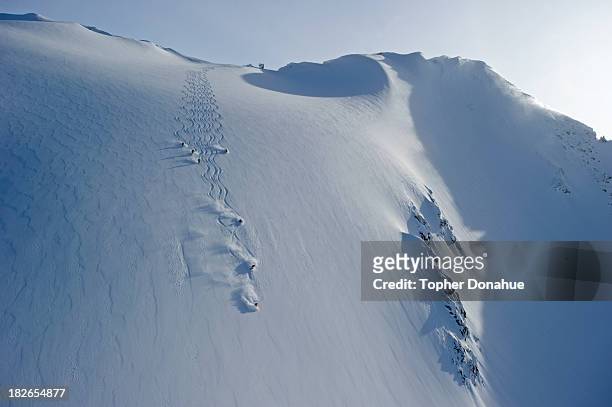 heliskiers on a steep face. - heli skiing stock pictures, royalty-free photos & images