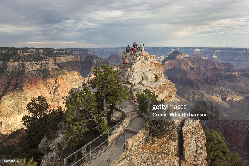 Tourists gather at a viewpoint overlooking a grand canyon landscape.