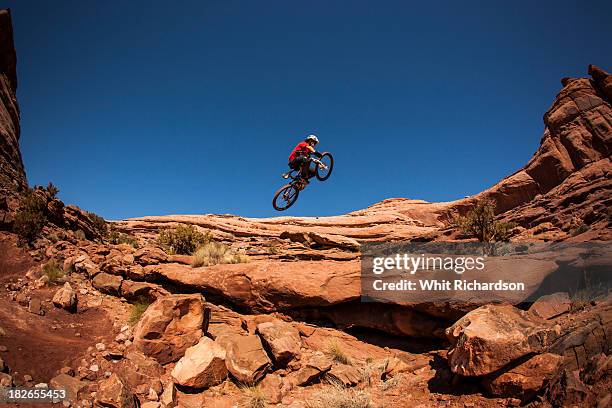 a man getting air on a jump on his montain bike near moab, utah. - stunt stock pictures, royalty-free photos & images