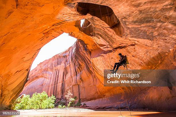 a man rapelling while canyoneering in a desert canyon. - abseiling stock pictures, royalty-free photos & images