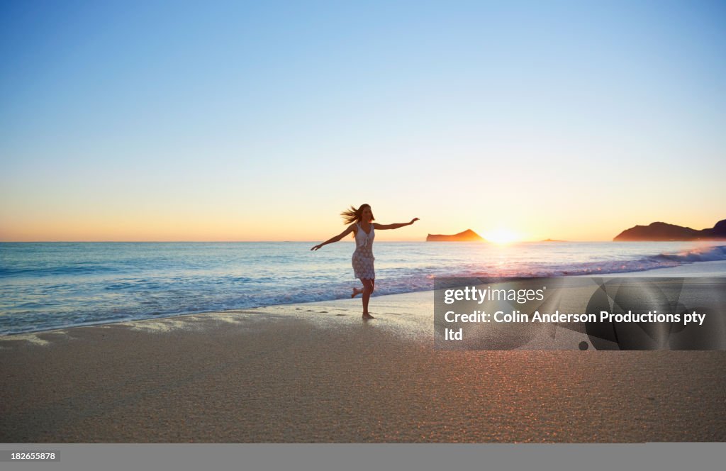 Pacific Islander woman playing in waves on beach