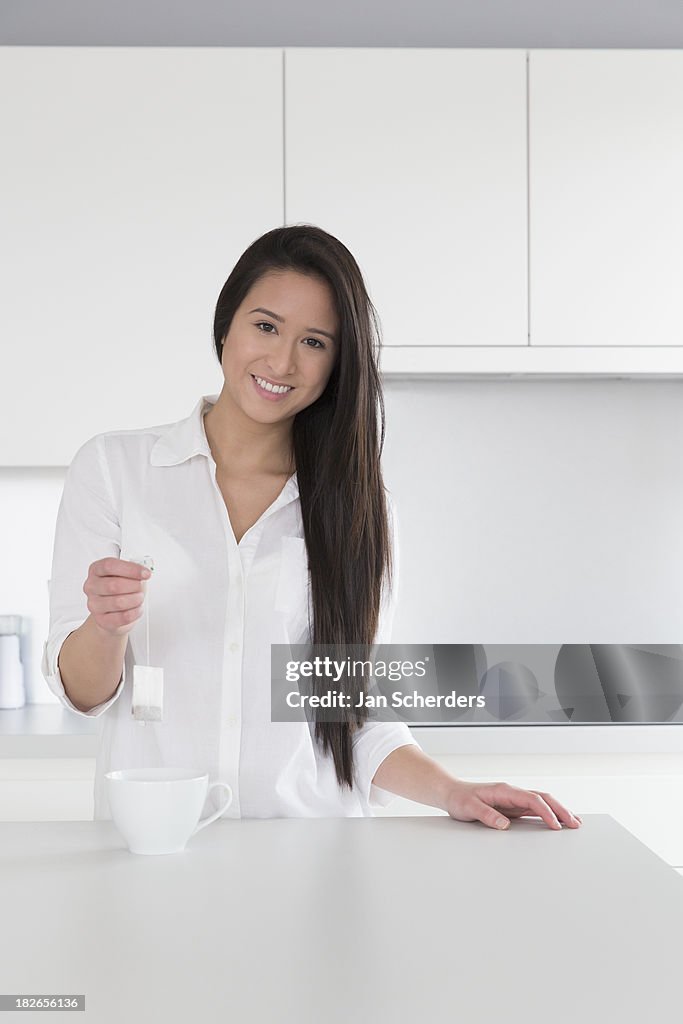 Mixed race woman having cup of tea in kitchen