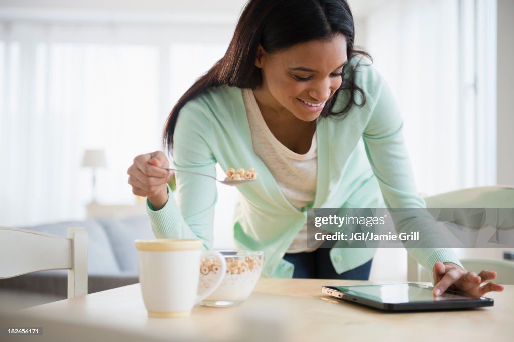 Mixed race woman using tablet computer at breakfast