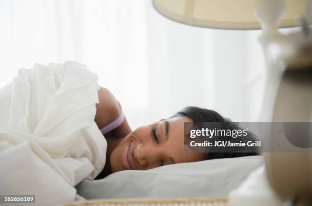 mixed race woman sleeping in bed - lying on side stock pictures, royalty-free photos & images