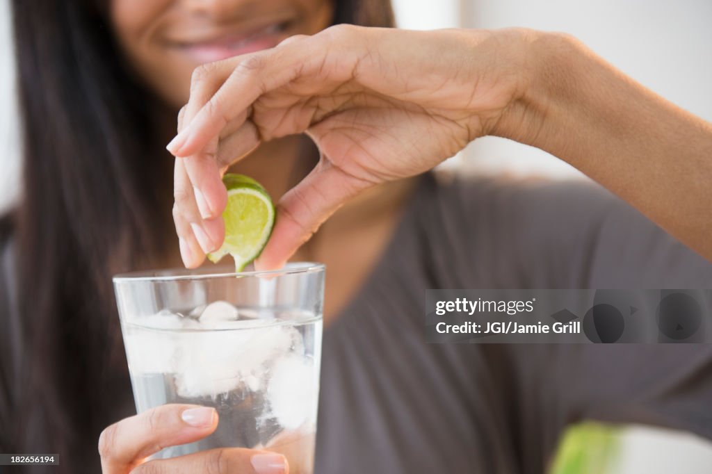 Mixed race woman squeezing lime into drink