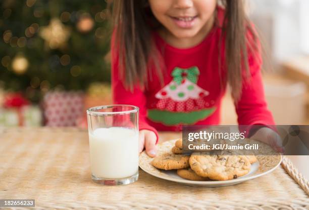 hispanic girl setting out milk and cookies for santa - milk and cookies stock pictures, royalty-free photos & images