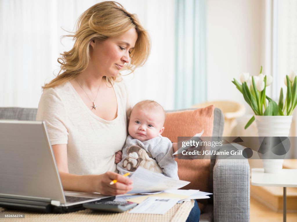 Caucasian mother with baby paying bills