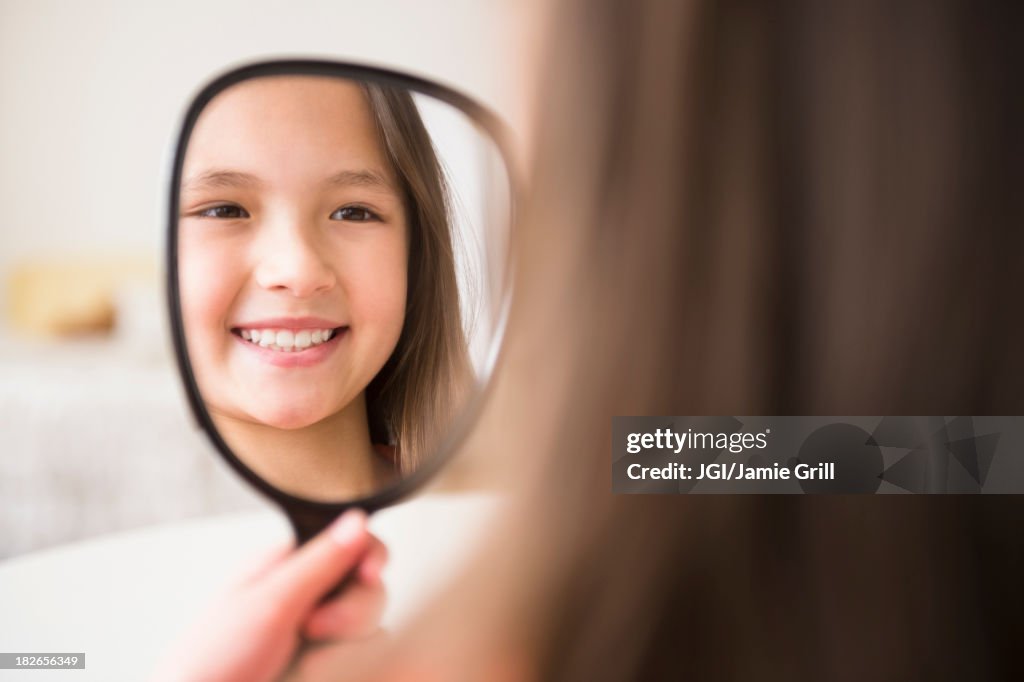 Mixed race girl admiring herself in mirror