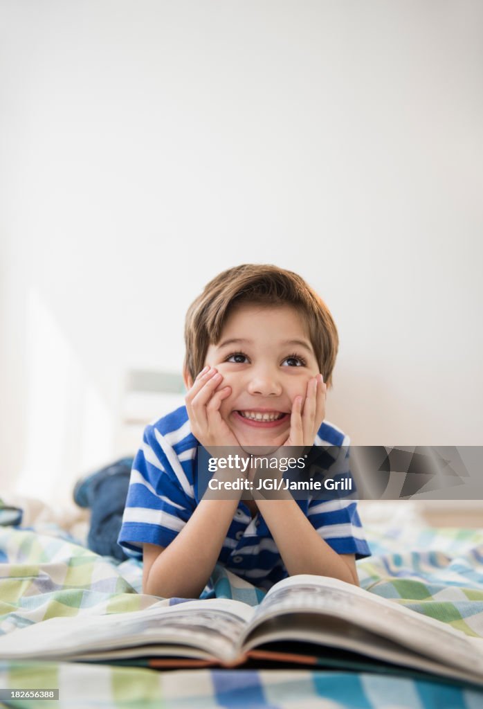 Hispanic boy reading on bed