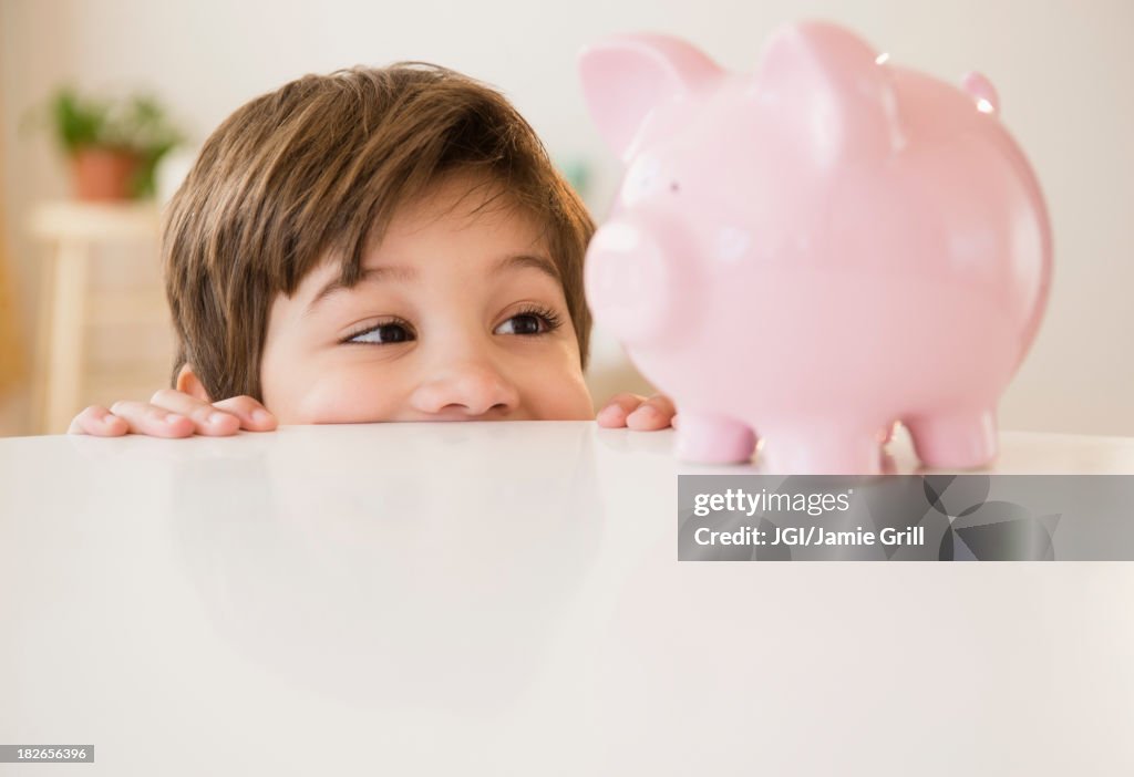 Hispanic boy examining piggy bank