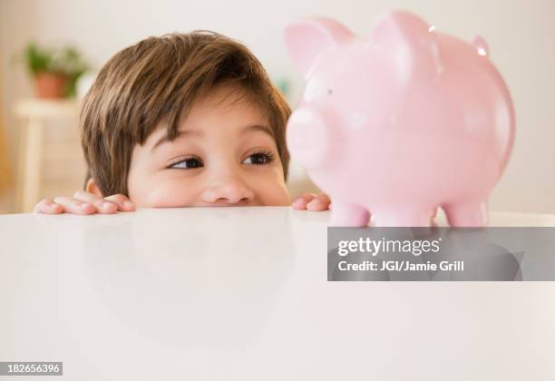 hispanic boy examining piggy bank - child saving stock pictures, royalty-free photos & images