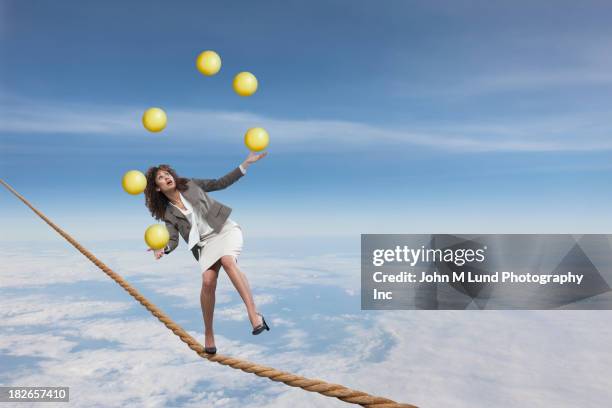 mixed race businesswoman juggling on tightrope - hochseil stock-fotos und bilder