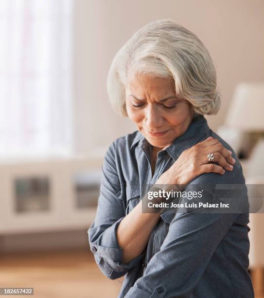 older black woman rubbing her shoulder - pain stock pictures, royalty-free photos & images