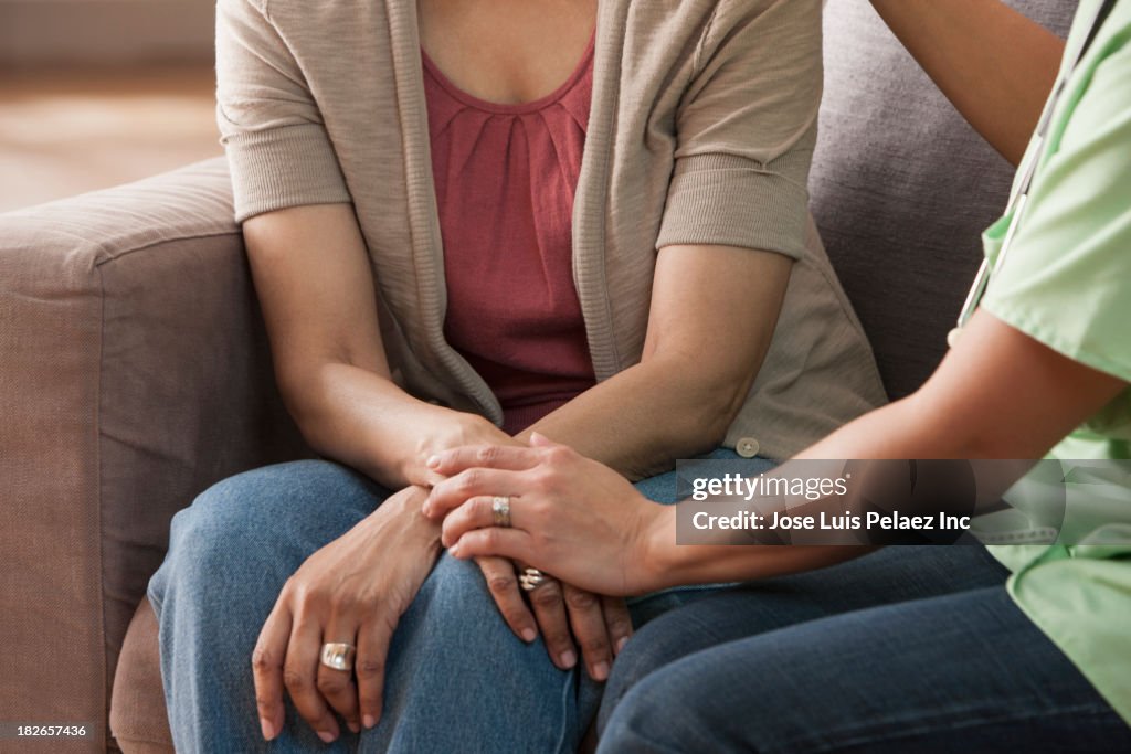 Mother and daughter holding hands on sofa