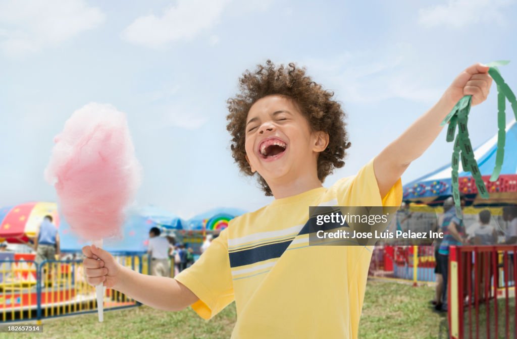 Mixed race boy with cotton candy and prize tickets at fair